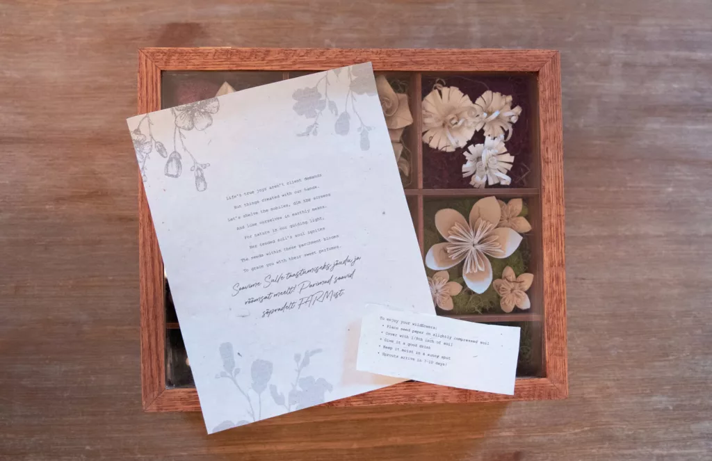 Image of letter on top of wooden box with origami flowers inside.