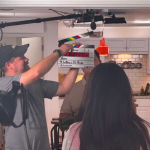 Behind the scenes of a commercial shoot. Man using a cue card in front of an actor's face.