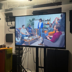 Behind the scenes of a commercial shoot. View of the monitor used by production with a scene of people in a living room on it.