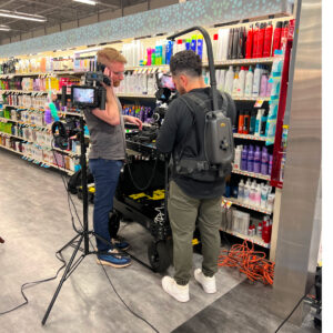 Behind the scenes of a commercial shoot. Crew reviewing footage before next scene in an aisle of the store.
