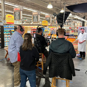 Behind the scenes of a commercial shoot. Crew filming a butcher in a Tops store.