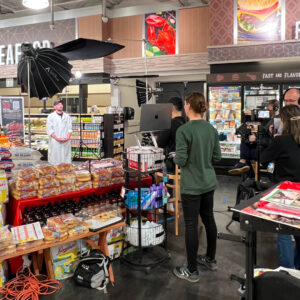 Behind the scenes of a commercial shoot. Crew filming a butcher in a Tops store.