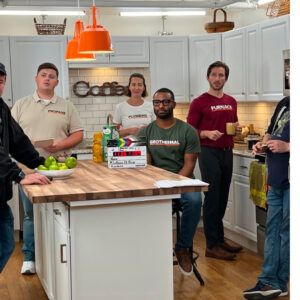 Behind the scenes of a commercial shoot. Group of actors sitting/standing around in a kitchen waiting for the next scene.