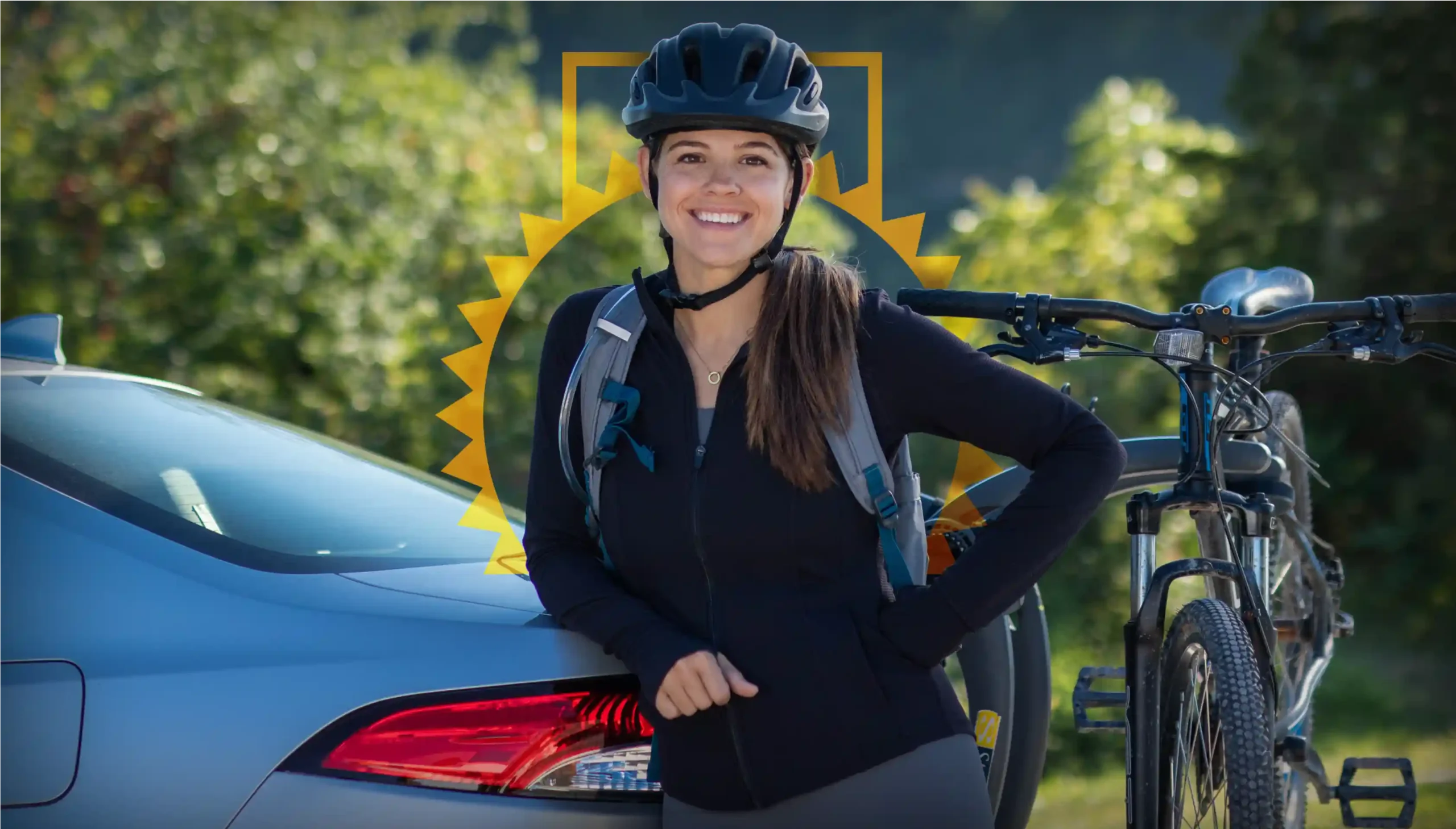 Women with biking gear on in front of a car with a bike on a bike rack.