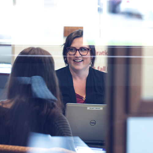 Woman with laptop in front of her laughing and looking to the left.