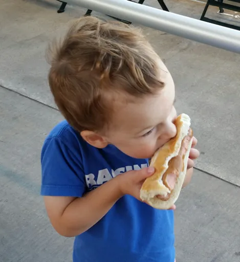 Image of young Wylie eating a hot dog like a cob of corn.
